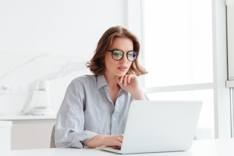 Charming businesswoman in glasses and striped shirt working with